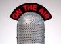 Retro microphone with an On the Air illuminated sign on a desk vignetted background